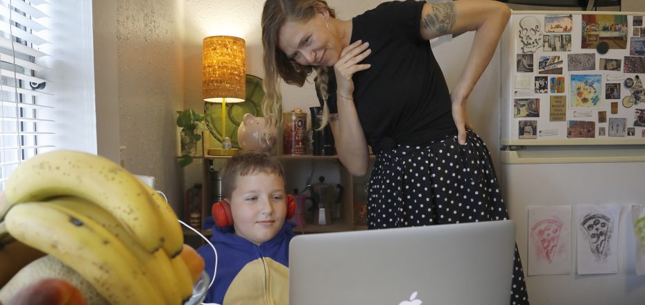 Allison Harris checks in on her son, 9-year-old Otto Nowicki, as he works on a distance learning assignment from Perkins Elementary in their kitchen Wednesday, April 8, 2020 in St. Petersburg, FL.