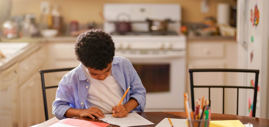 little boy in kitchen doing homework in the morning before school