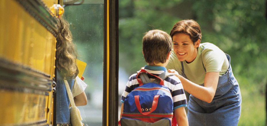 Mother sending son off to school at bus stop
