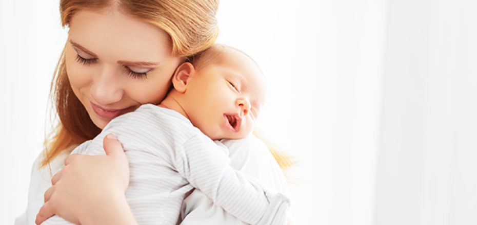 newborn baby in a tender embrace of mother at the window