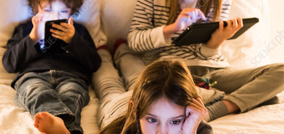 Children using a smartphone, a digital tablet and e-reader.